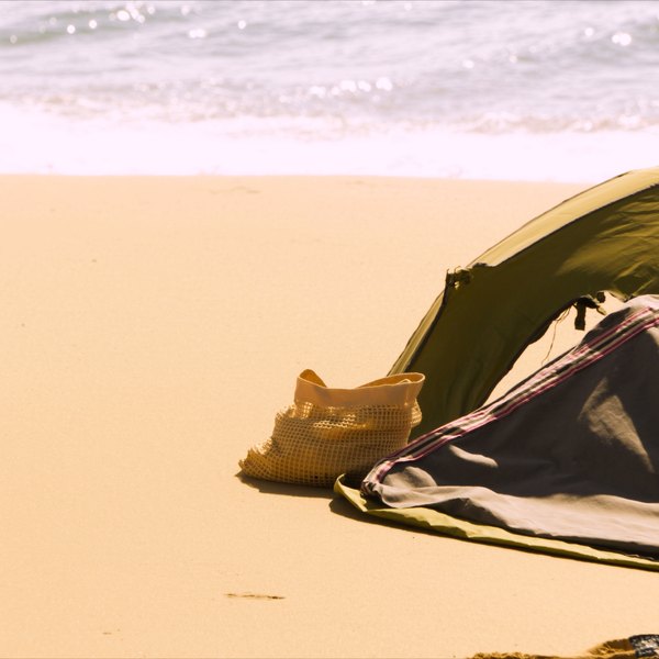 A budget beach day setup with a mesh bag and sun shade
