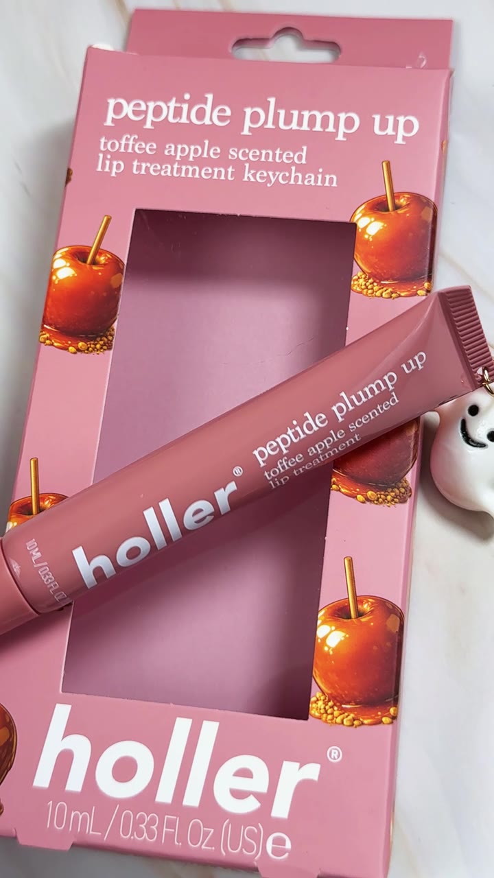 A Holler peptide plump up lip treatment being unboxed on a pink studio set.