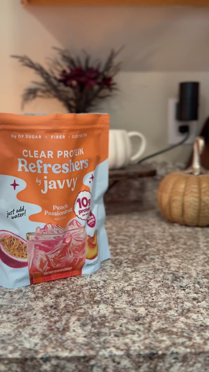 A Javvy Clear Protein Refreshers pouch on a kitchen counter beside a shaker cup.